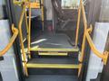 The interior steps of a 2017 Chevrolet Express with yellow handrails and a welcome sign on the floor guiding passengers to watch their step