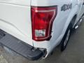 A white 2017 Ford F-150 with noticeable damage on the rear left quarter panel and tail light