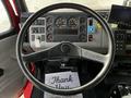 Dashboard and steering wheel of a 1994 Freightliner FL80 featuring gauges controls and a thank you mat on the floor