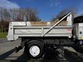 A 2011 International 7500 truck with a metallic dump bed and a raised tailgate mechanism