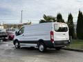 A 2023 Ford Transit van in white parked with its rear facing the camera showcasing its large cargo area and distinctive design