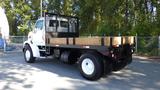 A 2007 Sterling Acterra L7500 flatbed truck with a wooden platform and a metal mesh backing, featuring yellow warning lights and a simple cab design