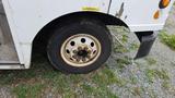 Close-up of a weathered tire and rim of a 2006 Ford Econoline showing dirt and rust on the metal surface