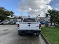 A white 2021 RAM 1500 truck viewed from the rear with a 4x4 badge on the tailgate standing in a parking area