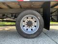 A close-up of a black tire mounted on a silver wheel with multiple lug nut holes showcasing a 2013 Ford F-450 SD's wheel assembly