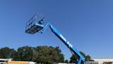 A blue 2008 Genie S-65 boom lift with an extended platform reaching upwards