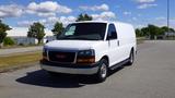 A white 2015 GMC Savana cargo van parked with a plain front design and the GMC logo prominently displayed on the grille