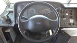 The image shows the steering wheel and dashboard of a 2011 Ford Econoline featuring gauges buttons and a key ignition