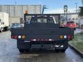 A black 2017 Ford F-350 SD with a flatbed and a protective mesh enclosure at the back featuring various lights and reflectors