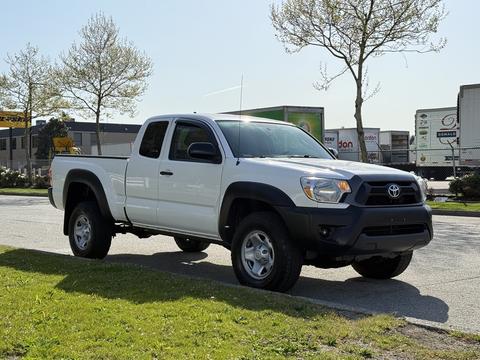 2015 Toyota Tacoma in white with a black front bumper parked on a street with a tall stance and four doors