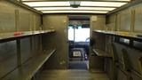 Interior of a 2011 Ford Econoline with empty shelves on both sides and a driver area visible at the front