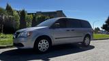 A 2016 Dodge Grand Caravan in silver with five-spoke wheels parked on a driveway