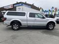 A silver 2014 Ford F-150 with a truck bed cover parked on a paved surface displaying its side profile and alloy wheels