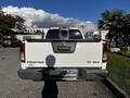 A white 2015 Nissan Frontier SV 4X4 truck viewed from the rear with its tailgate down and the model name prominently displayed on the tailgate