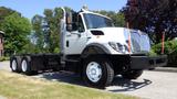 A 2013 International 7400 Workstar truck with a white cab and silver features parked with no cargo in the bed