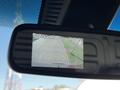 A rearview mirror displaying a camera feed with a warning to check entire surroundings