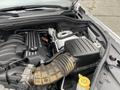 A 2018 Jeep Grand Cherokee engine compartment showing the engine block air intake and components with various hoses and a fluid reservoir