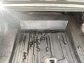 A 1966 Ford Mustang trunk with a black rubber mat and some water on the floor
