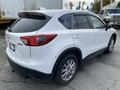 A white 2016 Mazda CX-5 SUV is shown from the rear angle highlighting its sleek design and chrome detailing on the taillights and wheels