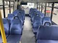 Interior view of a 2017 Chevrolet Express bus showing empty blue vinyl seats arranged in rows along each side of the aisle