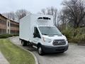 A white 2018 Ford Transit box truck with a refrigerated unit on the roof and chrome wheels parked on a curved driveway