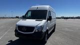 A 2016 Mercedes-Benz Sprinter van with a white exterior and black grille positioned at an angle facing forward