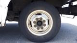 A close-up of a white wheel from a 2011 Ford Econoline featuring a circular rim and a large black tire with visible lug nuts