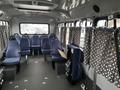 Interior view of a 2012 Chevrolet Express with blue fabric seats arranged in rows and curtains at the windows