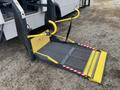 A yellow and black ramp designed for accessibility extends from a 2017 Chevrolet Express with safety features including handrails and a textured surface