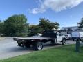 A 2013 Ford F-450 SD truck with a flatbed and a black metal bedliner is parked on a gravel surface