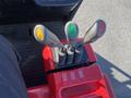 Close-up of the control levers on a 2013 Raymond Forklift featuring three handles in yellow green and red colors with textured grips and labeled buttons below