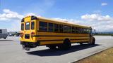 A yellow 2014 International 3000 school bus parked on a paved area viewed from the rear with large windows and distinct black accents