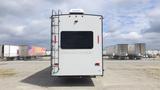 A 2021 Forest River Cedar Creek travel trailer viewed from the rear featuring a ladder on the side and large rear window with the brand name displayed beneath it