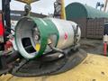 A silver and green gas cylinder mounted on a yellow forklift with a black hose and connector visible near the base of the cylinder