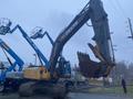 A 2014 John Deere 350G excavator with a large bucket attachment standing prominently in the foreground