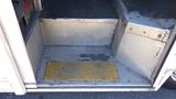 A 2006 Ford Econoline interior step with a yellow metal plate on a textured floor showcasing aluminum steps and rubber matting