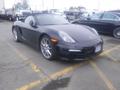 A black 2016 Porsche Boxster with a convertible top and silver alloy wheels parked in a lot