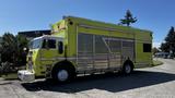 A bright yellow 1995 Freightliner FLL086 with metal sliding doors and a prominent front grille parked on the street