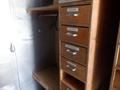 A wooden cabinet with several labeled drawers including categories like clothing and miscellaneous items