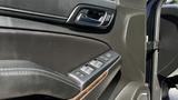 Close-up of the driver's side door panel of a 2018 Chevrolet Tahoe featuring window control buttons and a wood accent trim