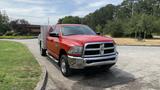 A red 2013 RAM 2500 pickup truck with a silver truck bed and chrome accents parked on a paved surface