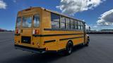 A yellow 2014 Freightliner Thomas Diesel school bus with large windows and black trim parked on a lot