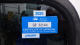 A 2009 Hino 338 garbage truck with a blue certificate of approval sticker displaying the year 2025 and an expiration date label for January