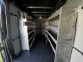 Interior of a 2021 Mercedes-Benz Sprinter van featuring metal shelving units along both sides for storage