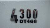 The image features the shiny chrome badge of a 2005 International 4300 with the model number 4300 and engine designation DT466 covered in water droplets