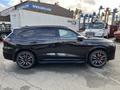 A 2023 Acura MDX in black with sporty red brake calipers and alloy wheels viewed from the side