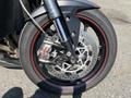 A close-up view of the front wheel of a 2018 Triumph Street Triple RS showcasing the Brembo brake caliper and a tire with a red stripe