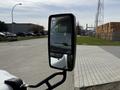 Side mirror of a 2010 Ford Econoline reflecting the road and buildings in the distance