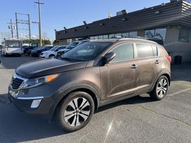 A 2012 Kia Sportage parked at a dealership with a dirty exterior and stylish alloy wheels