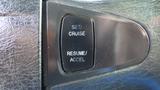 Close-up of a cruise control panel featuring buttons labeled Set Cruise and Resume Accel on a textured black surface